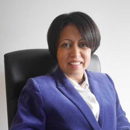 Professional headshot of a woman in her 40s with short dark hair, warm neutral background